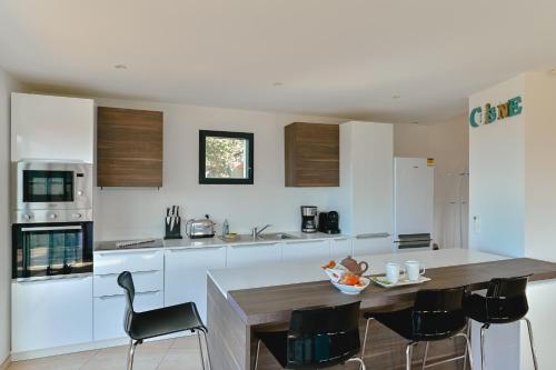 a kitchen with white cabinets and a table and chairs at Villa à l'entrée de Porticcio - Piscine - Vue dégagée in Cauro