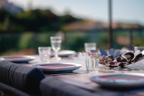 a wooden table with plates and glasses on it at Villa à l'entrée de Porticcio - Piscine - Vue dégagée in Cauro