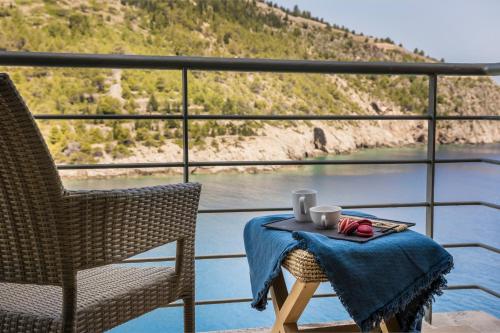 a table and chairs on a balcony with a view of the water at Braunis Horio Villas in Asos