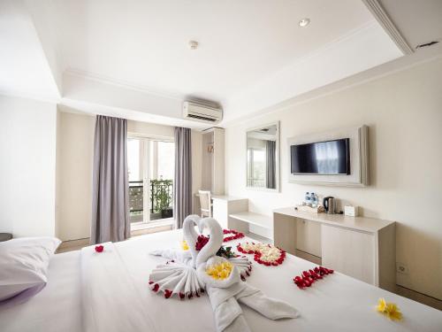 a hotel room with a bed with flowers on it at Alron Hotel Kuta Powered by Archipelago in Kuta