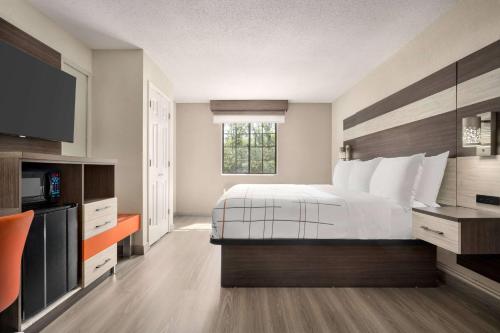 a hotel room with a bed and a flat screen tv at La Quinta Inn Lexington-Horse Park in Lexington