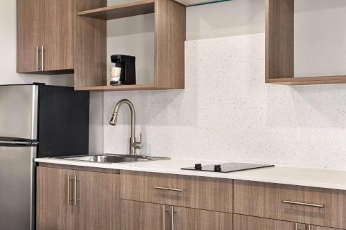 a kitchen with wooden cabinets and a stainless steel refrigerator at La Quinta Inn by Wyndham Temple in Temple