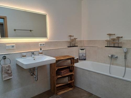 a bathroom with a sink and a tub and a mirror at Ferienwohnung zum Peterbauer in Sachsenkam