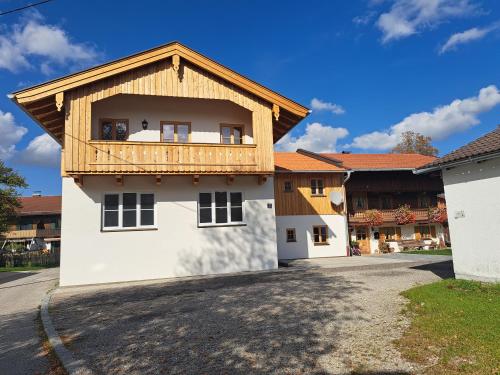 a white building with a wooden balcony on top of it at Ferienwohnung zum Peterbauer in Sachsenkam