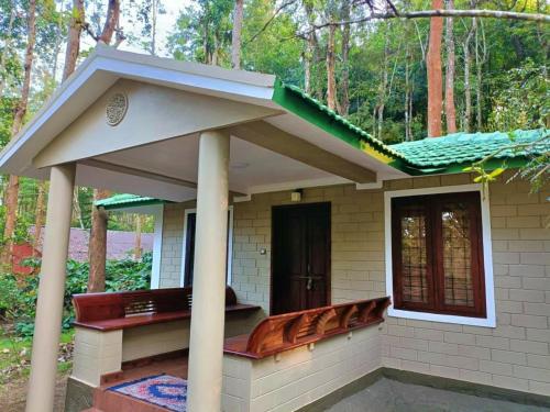 a small house with a pitched roof and a bench at Adrak Mountain Mist Forest Resort in Pulpally