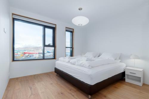 a white bedroom with a large bed and a window at Blue Viking Apartments Reykjavik in Reykjavík