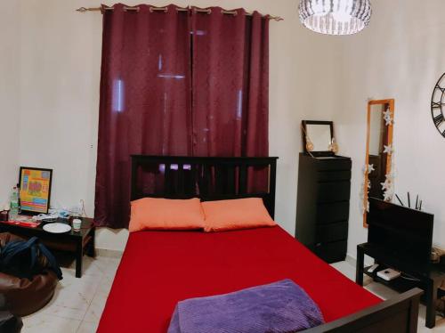 a bedroom with a red bed in front of a red curtain at Full Apartment in Central Al Ain (All Amenities) in Al Ain