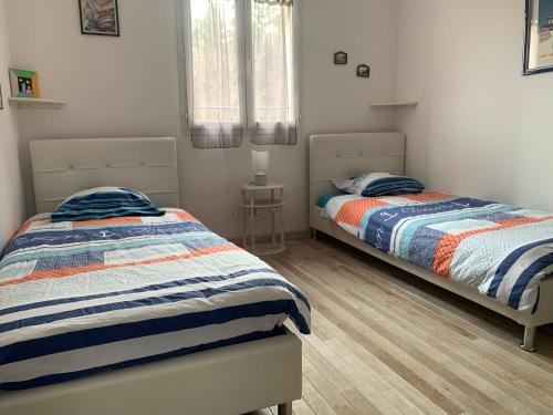 two twin beds in a bedroom with wooden floors at Villa de charme avec piscine chauffée, Jacuzzi et Sauna in Taradeau