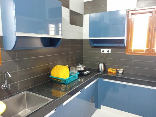uma cozinha com armários azuis e um lavatório em Meadows Homestay em Madurai