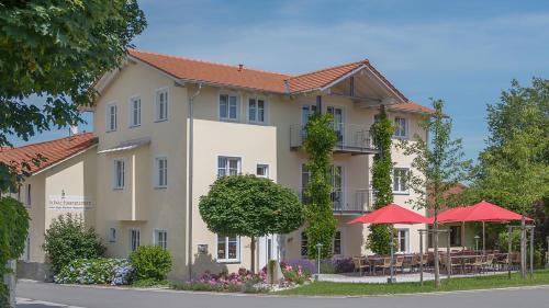 a building with tables and umbrellas in front of it at Zum Kirchenwirt in Neukirchen vorm Wald