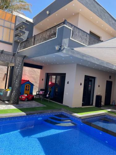a house with a swimming pool in front of it at Villa Jana chalet - Private Villa - Dead Sea - Jordan in Ash Shāghūr