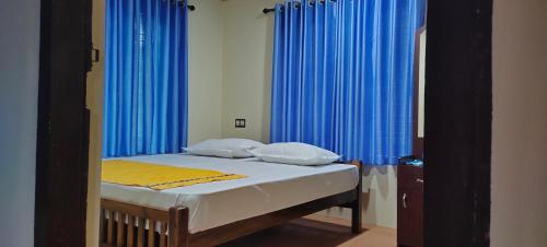 Schlafzimmer mit einem Bett mit blauen Vorhängen in der Unterkunft PONMUDI DALE. HOMESTAY in Kallar-Bridge