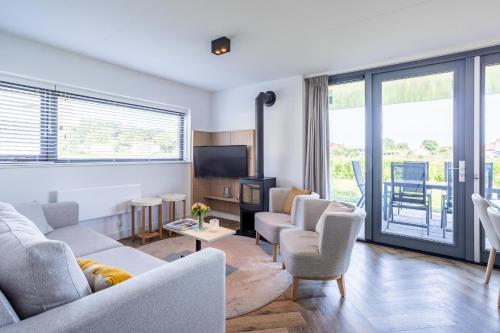 a living room with a couch and chairs and a tv at Duyndomein Noordwijk in Noordwijk