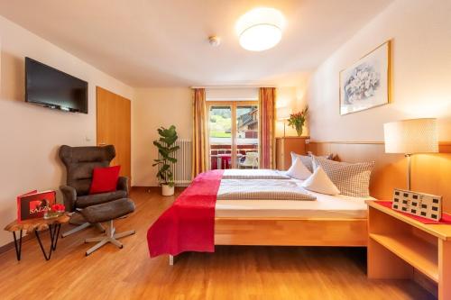 a bedroom with a large bed and a chair at Familien- und Wellnesshotel "Viktoria" in Oberstdorf