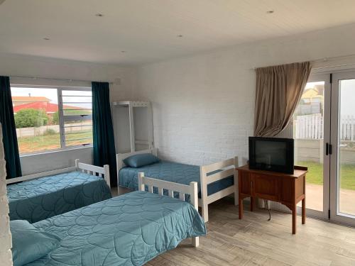 a bedroom with two beds and a tv and a television at Strandfontein holiday house in Strandfontein