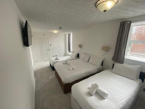 a hotel room with two beds and a television at The Fairhaven Hotel in Weymouth