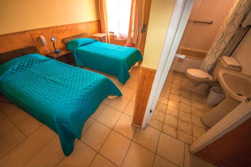 a room with two beds and a bathroom with a toilet at Hotel Montecarlo in Caldera