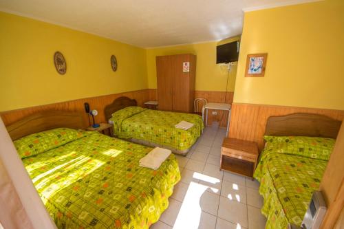 a hotel room with two beds and yellow walls at Hotel Montecarlo in Caldera