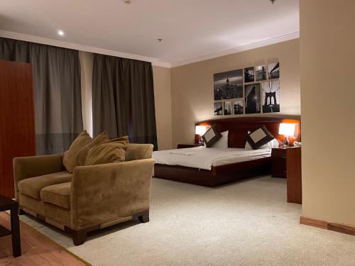 Al WakrahにあるWakra Inn Hotel Apartmentsのベッドルーム1室(ベッド1台、ソファ、椅子付)