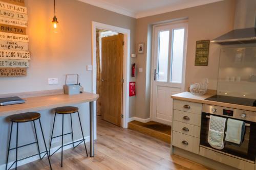 a kitchen with a counter and two bar stools at Corner Cottage - character, charm, great location. in Ringwood