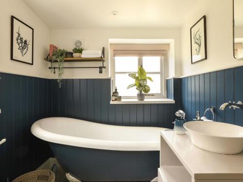 Salperton的住宿－Grove Cottage，蓝色和白色的浴室设有浴缸和水槽