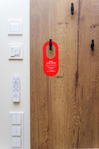 a red tag is hanging on a wooden door at Hotel TwentyFour Living in Bad Urach