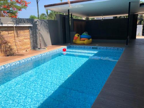een zwembad met twee speeltjes naast een huis bij PoolVilla Breeze Valley in Cha Am