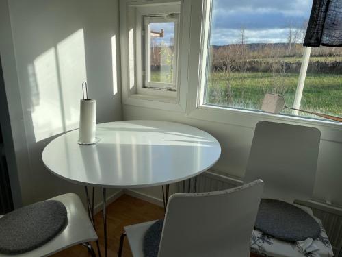 a white table and chairs in a room with a window at Two small Guest houses by lake rent out as One in Hjo