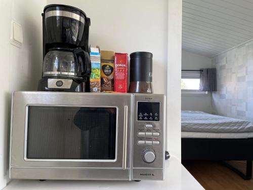 a microwave with a coffee maker on top of it at Two small Guest houses by lake rent out as One in Hjo