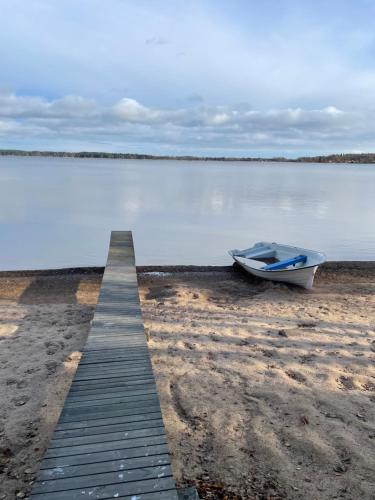 a boat sitting on the beach next to a dock at Two small Guest houses by lake rent out as One in Hjo
