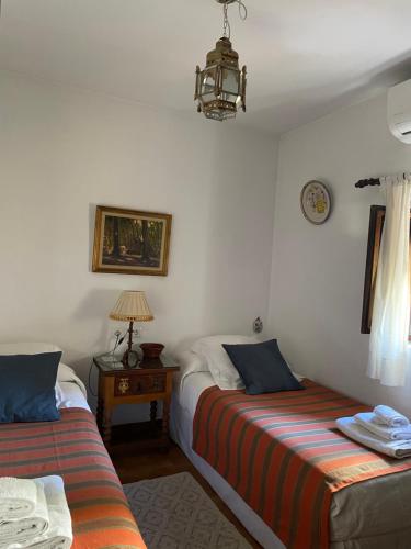1 dormitorio con 2 camas y mesa con lámpara en La Casita del Corralon en Granada