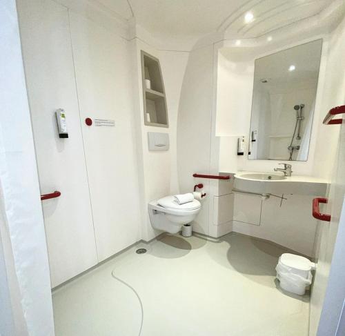 a white bathroom with a toilet and a sink at LOGIS - Hôtel & Restaurant le Grand Terre in Chartronges
