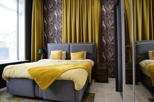 a bedroom with a bed with a yellow blanket on it at De Oude Pastorie Lisse in Lisse