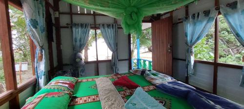 a bed in a room with two windows at Baan Suan Kayoo 2 Buffalo Bay Aow Khao Kwai in Ko Phayam