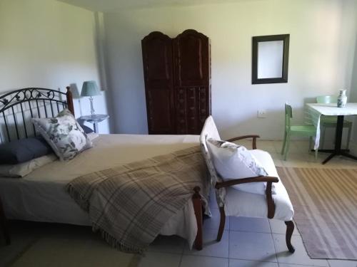 1 dormitorio con 1 cama, 1 silla y 1 mesa en Crossroads Guestrooms en Gordonʼs Bay