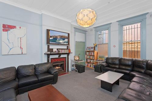 sala de estar con sofás de cuero y chimenea en PodBed Sydney en Sídney