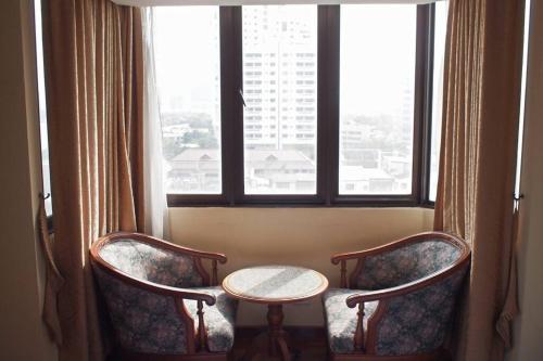 バンコクにあるSpacious room 55 sq.m. Central BKK close to Nana BTSの椅子2脚、テーブル、窓が備わる客室です。