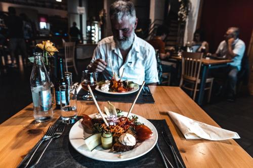a man sitting at a table with two plates of food at Hotel Cornelyshaff in Heinerscheid