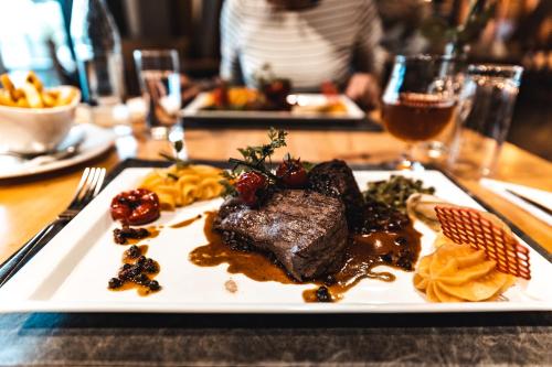 a plate of food with steak on a table at Hotel Cornelyshaff in Heinerscheid