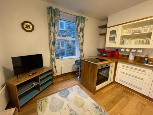 a kitchen with white cabinets and a tv on a counter at Flat 2, Ty Newydd in Barmouth