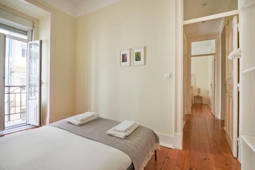 una camera bianca con un letto e una finestra di Renovated Spacious Baixa Apartment, By TimeCooler a Lisbona