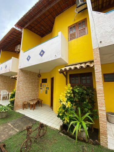 una casa amarilla con una mesa delante en Duplex em condomínio no Barra Mar en Barra de São Miguel