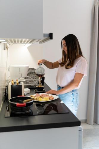 a woman standing in a kitchen with a plate of food at Alpha Studios Naxos - Adults Only in Naxos Chora