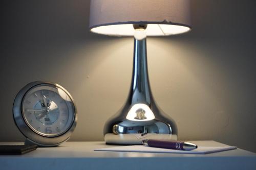 a desk with a lamp and a pen and a clock at VIP@TheMeadows in Portadown