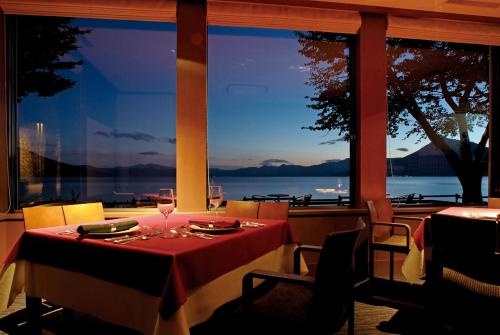 a dining room with a table with a view of the water at Shikotsuko Onsen Lake Side Villa SUIMEIKAKU-Adult Only in Chitose