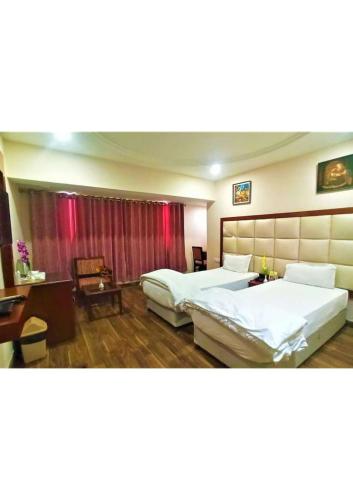 una camera d'albergo con 2 letti e una scrivania di Shining star a Bodh Gaya