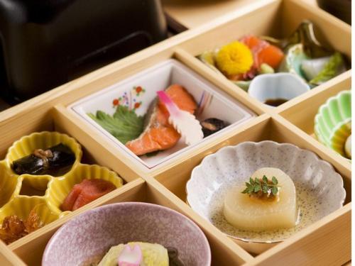 uma caixa de madeira cheia de diferentes tipos de alimentos em Shikotsuko Onsen Lake Side Villa SUIMEIKAKU-Adult Only em Chitose