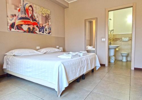 a bedroom with a large white bed with a bathroom at B&B Viale San Pietro in Sassari