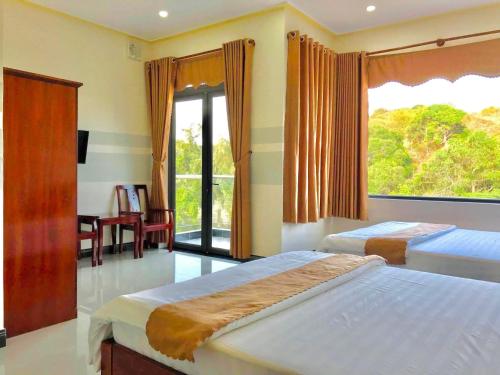 a bedroom with two beds and a large window at Quang Vinh Hồ Tràm in Ho Tram