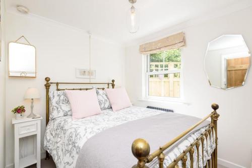 a white bedroom with a bed and a mirror at Bijou Coastal Apartment in Polperro with Onsite Parking in Polperro